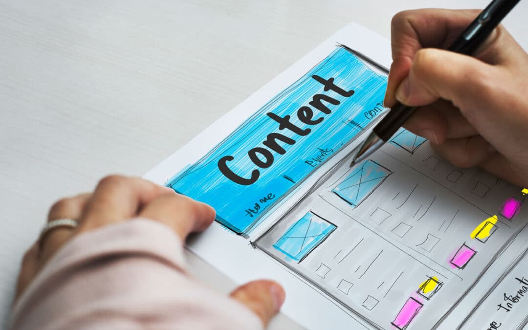 A person sketches a website layout labeled Content with sections and boxes, using colored markers on paper—perhaps inspired by tips from a Content Marketing Consultant. The hand holding a pen is drawing, with a sleeve partially visible.