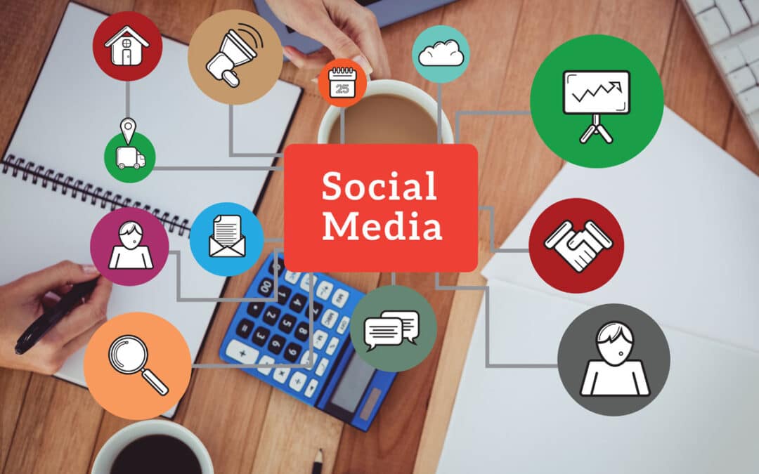 A person works at a desk with a notebook, calculator, and coffee. Around the words “Social Media” are colorful icons illustrating communication, business, and marketing—highlighting the benefits of an effective social media strategy.